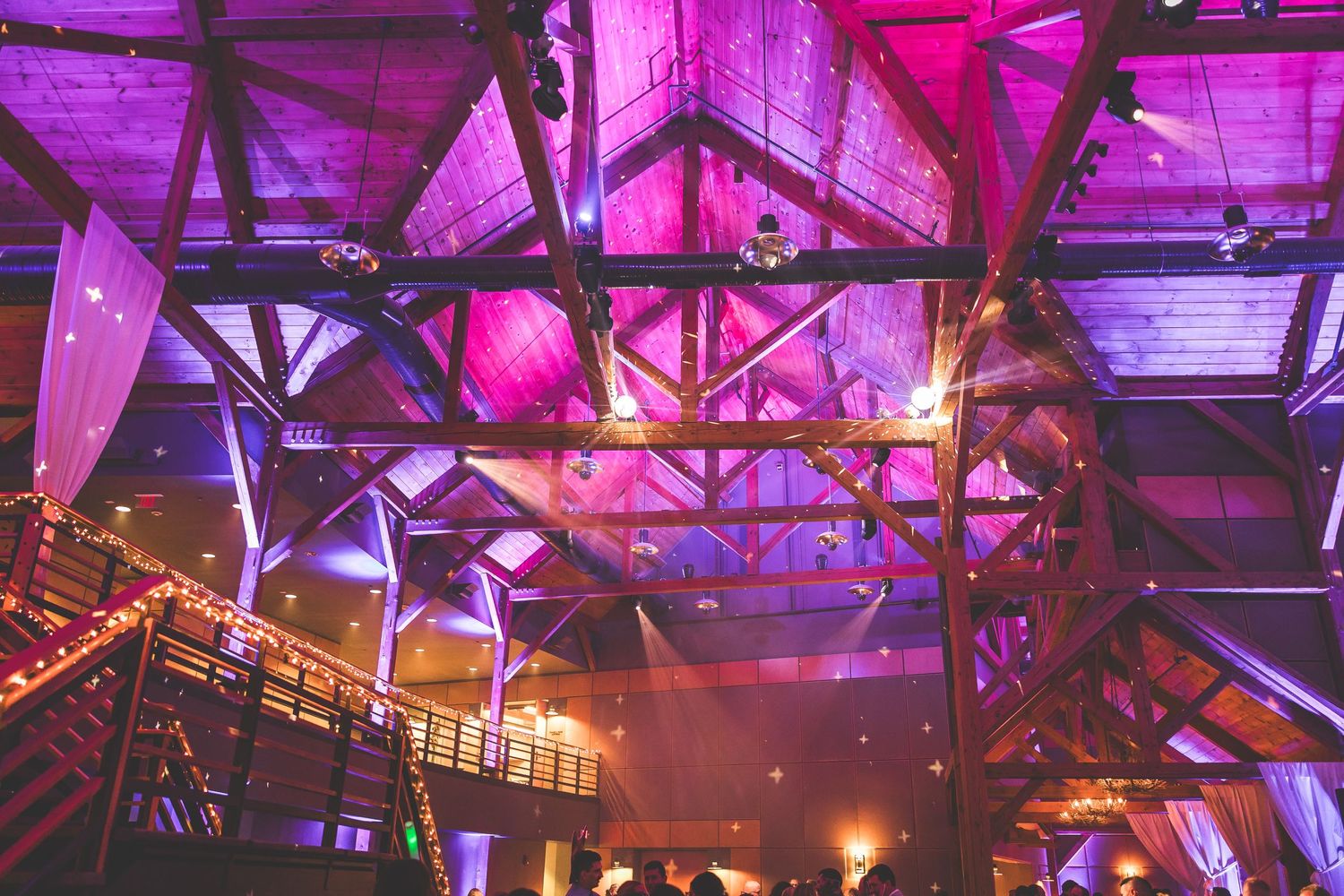 Rustic barn venue illuminated with dramatic purple and pink uplighting for evening reception.