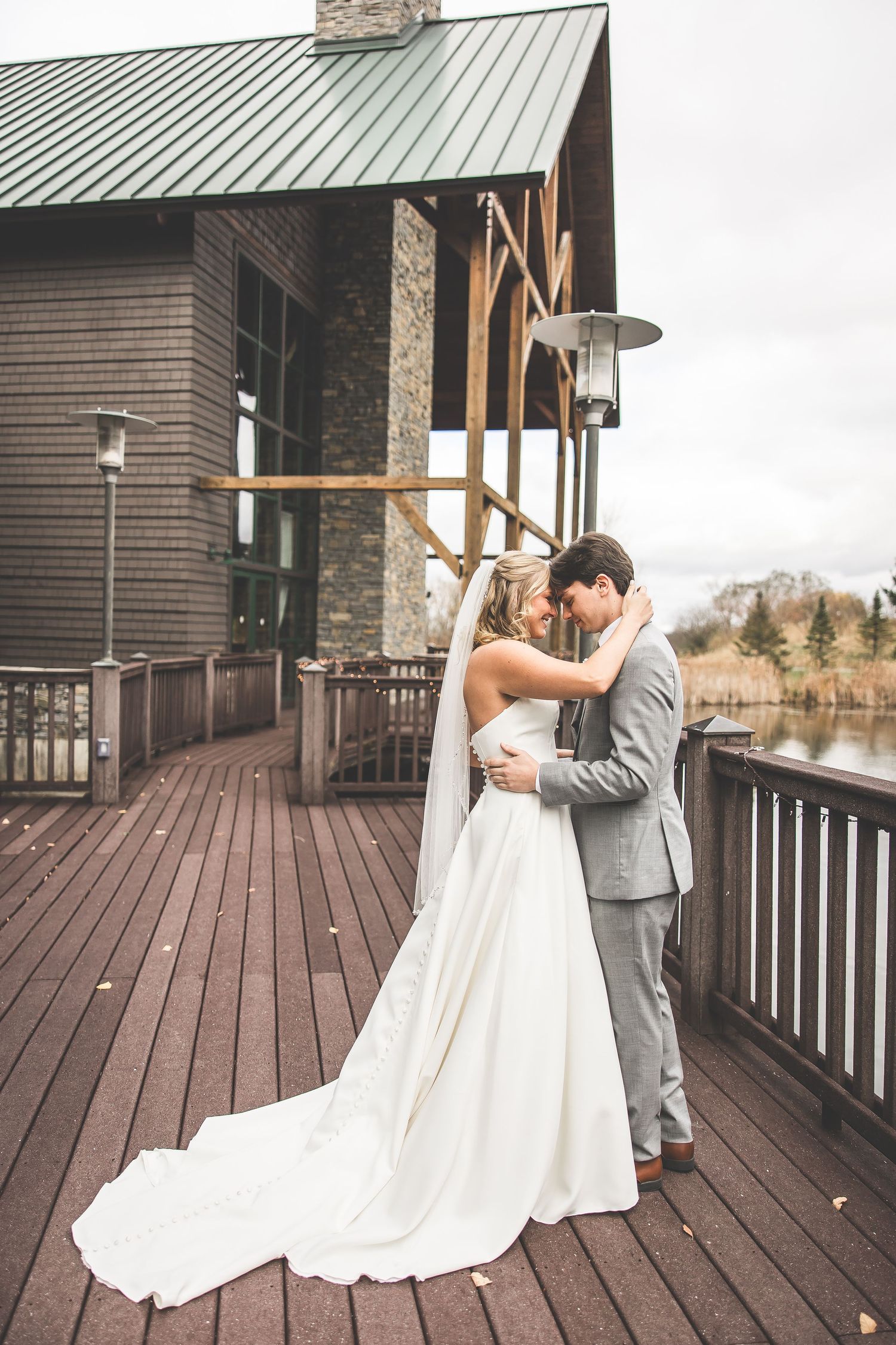 Bride and groom share their first look on a rustic wooden deck.