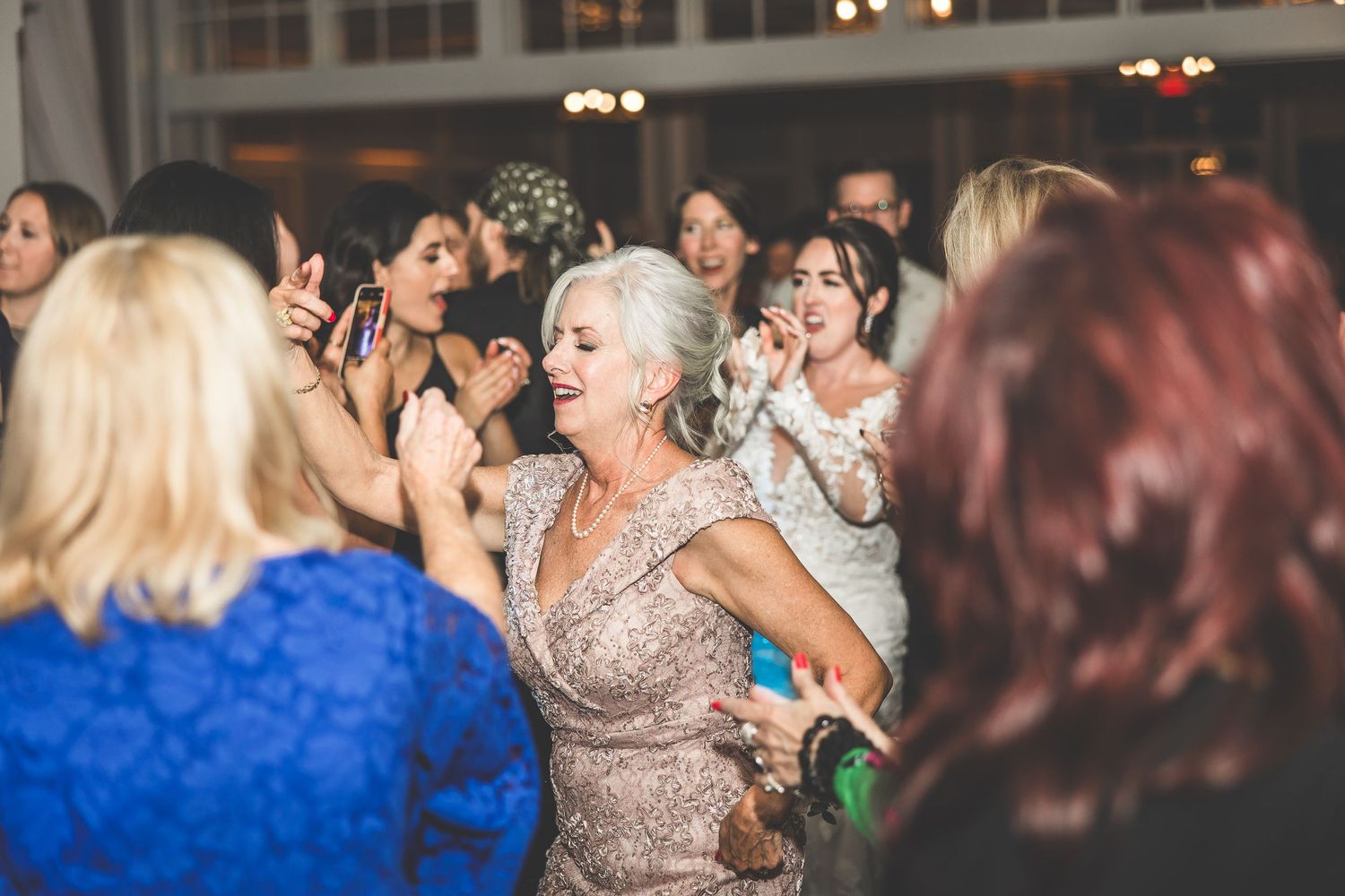 Wedding guests dancing and celebrating on a lively reception dance floor.