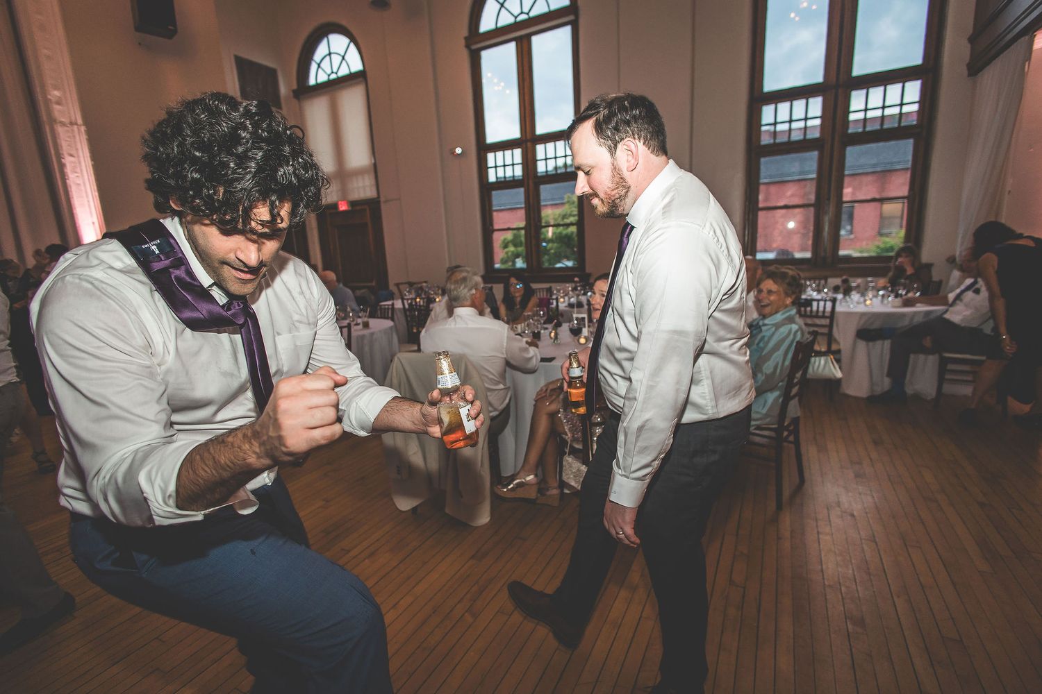 Two guests chatting and relaxing at a wedding reception with hardwood floors.