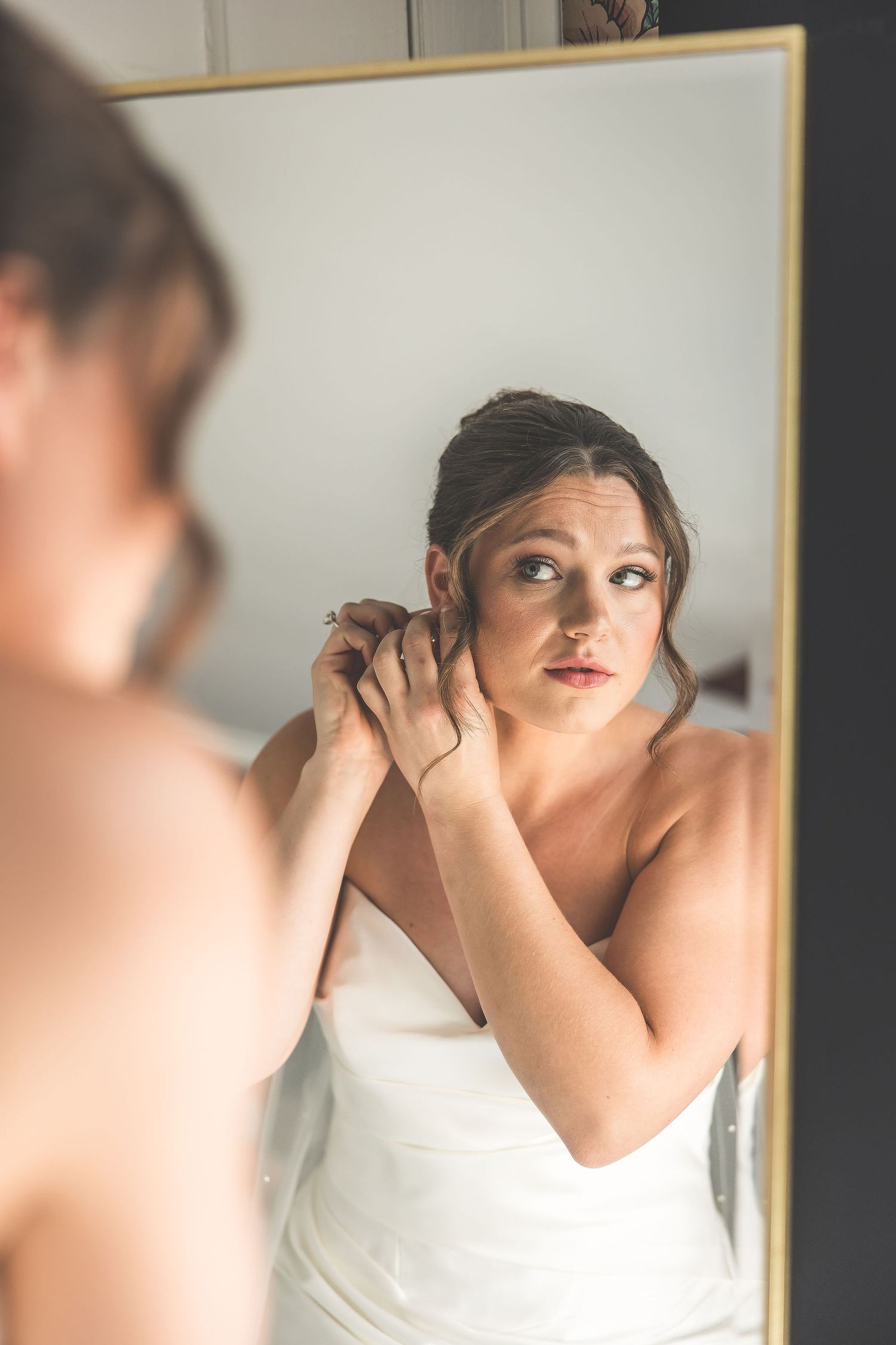 A mirror reflection captures final touches being made to wedding day hair and makeup.