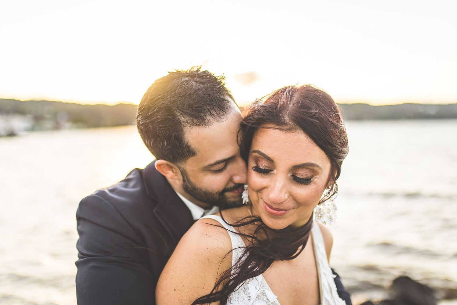 Romantic sunset portraits of couple by ocean with soft golden lighting.