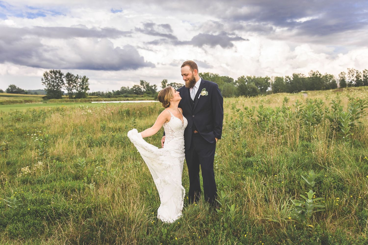 Newlyweds dance and twirl together in a scenic field during their wedding photoshoot.