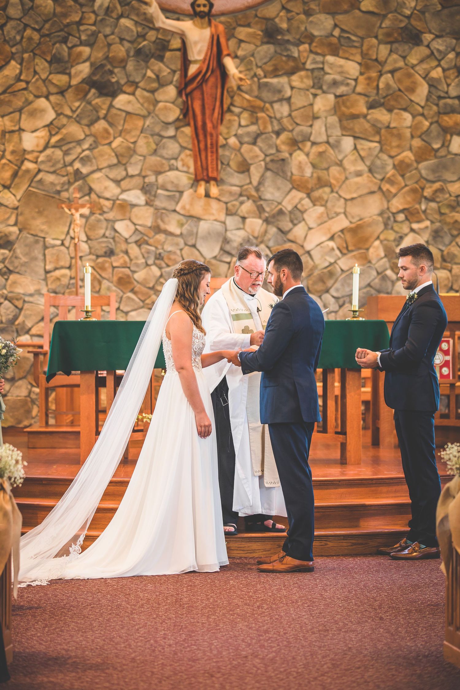 Wedding ceremony progression shots against a stone wall with religious imagery.