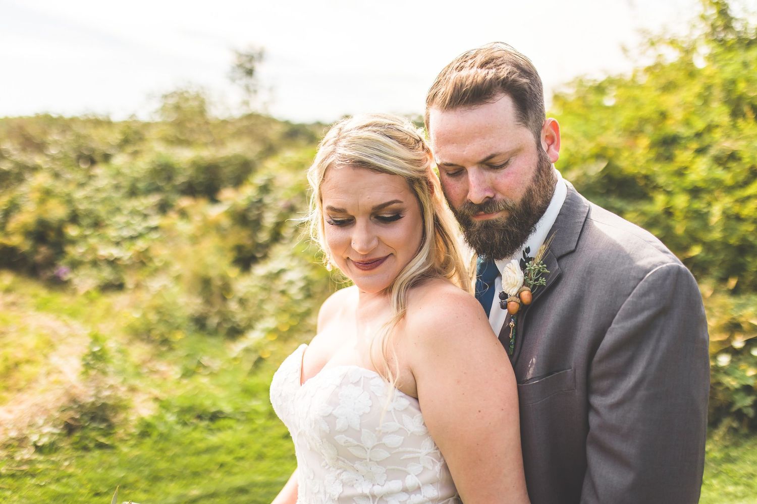 Candid wedding portraits captured in golden afternoon light amidst natural outdoor scenery.