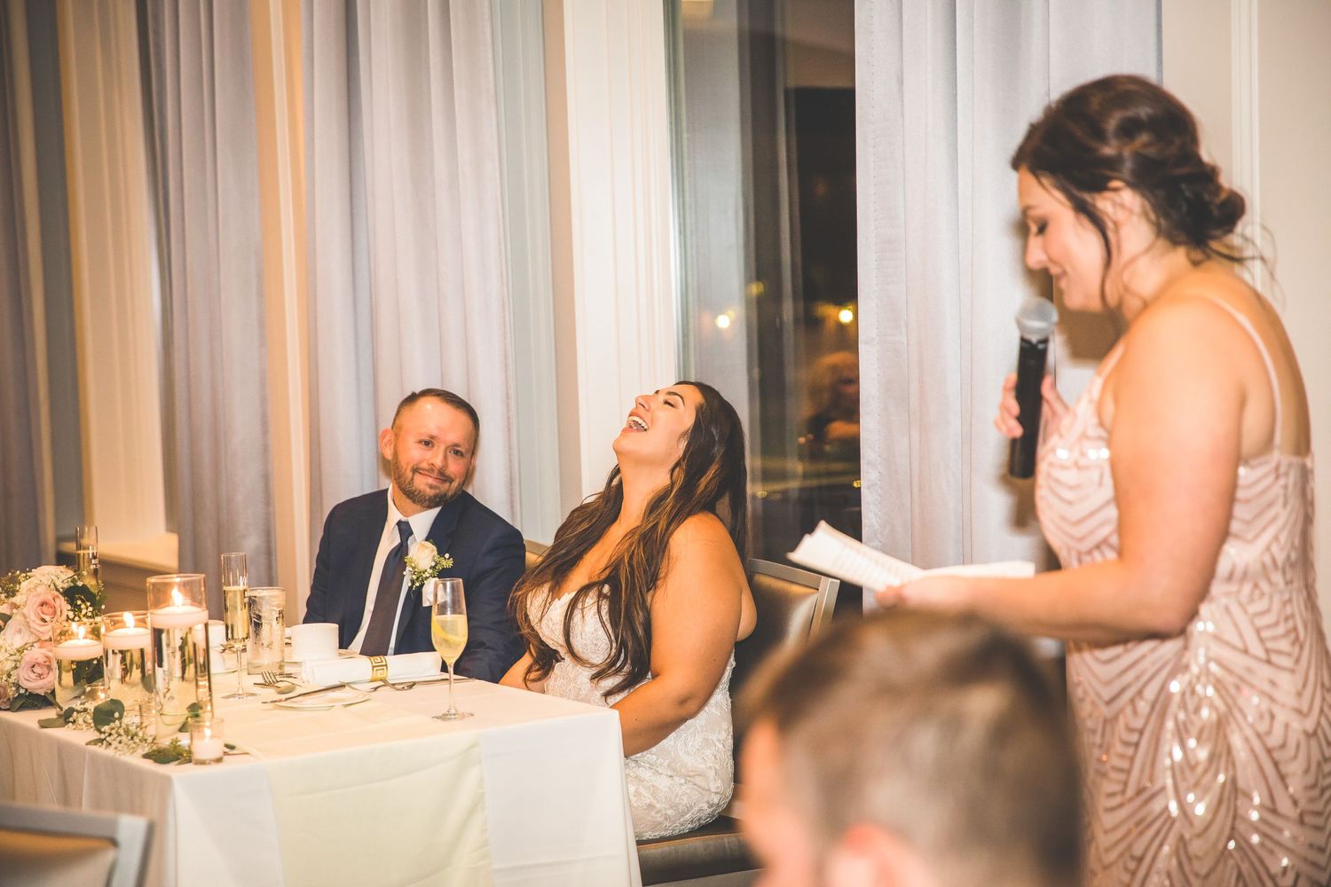 Wedding reception guests seated at decorated tables during evening celebration.