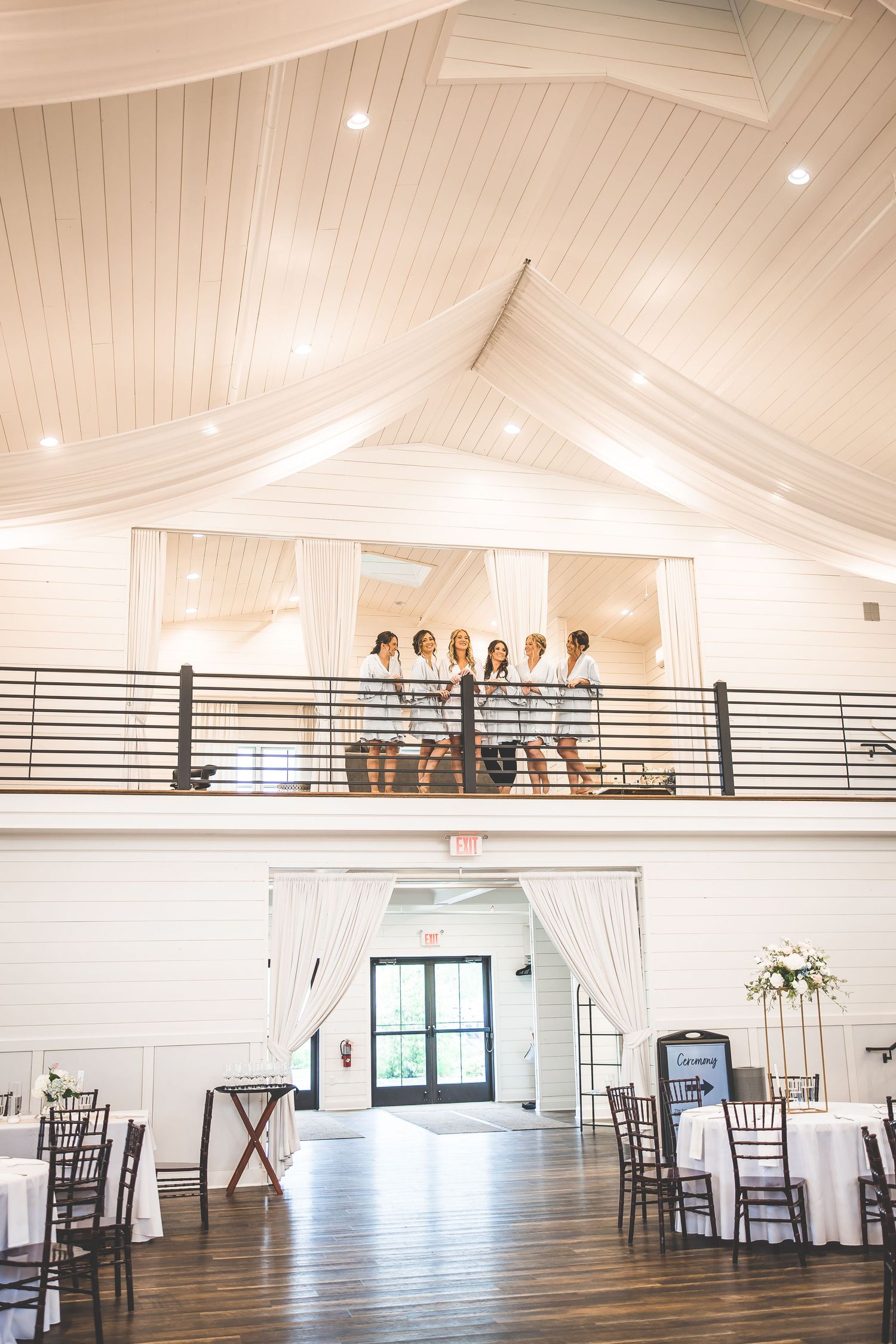 Spacious white wedding venue with high ceilings and elegant draping.