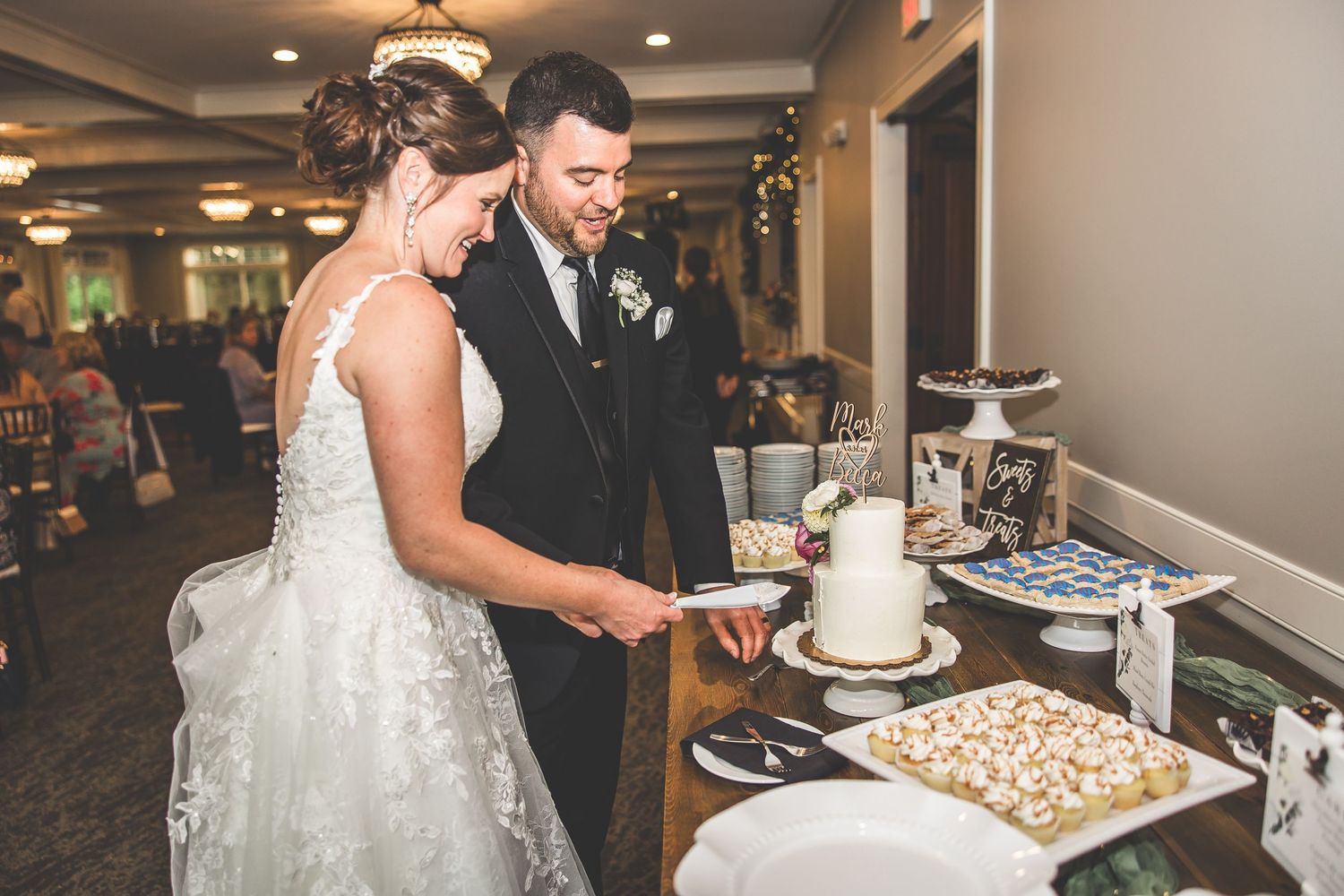 Wedding couple shares cake at their reception in an elegant ballroom.