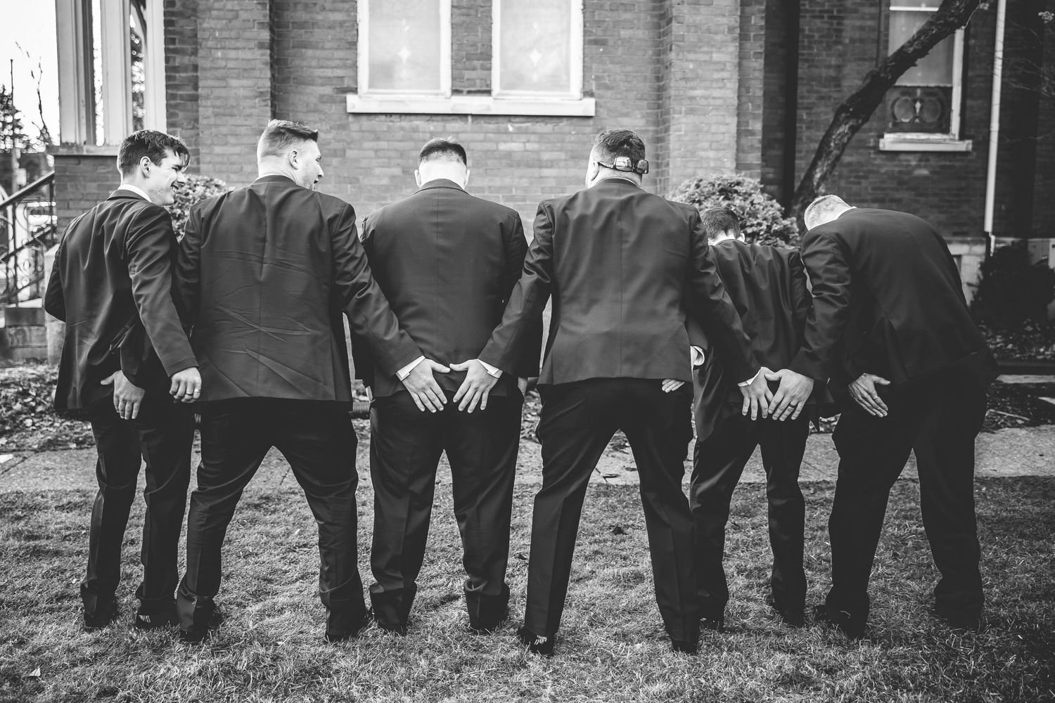 Black and white photo of wedding party members lined up outside historic building.