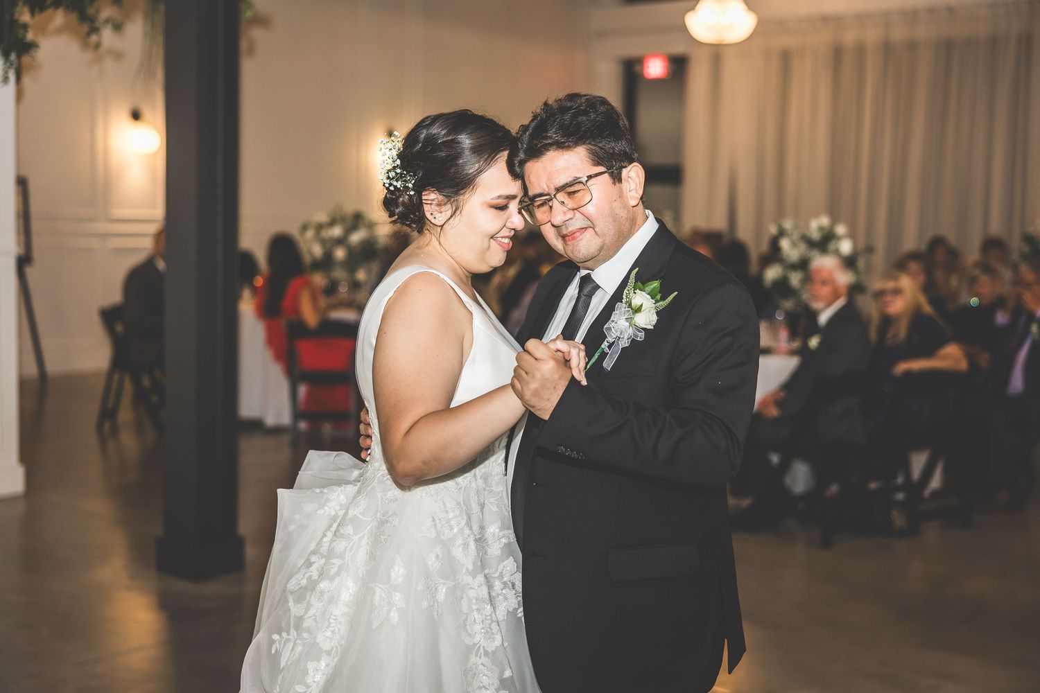 Wedding celebration candids in an elegant white-walled reception venue.