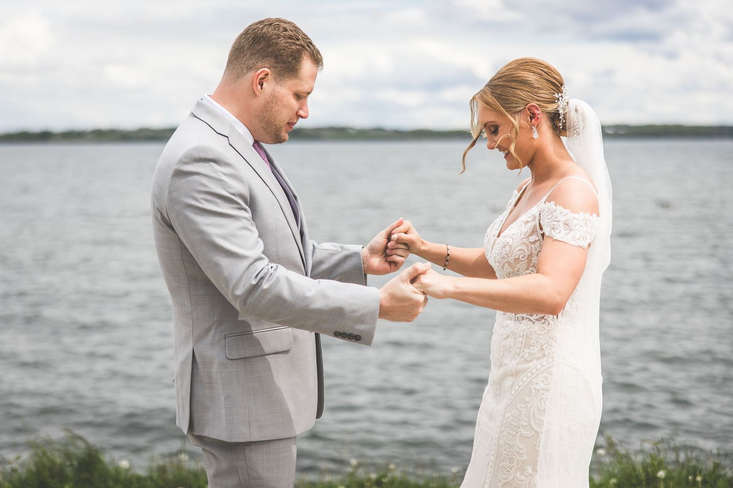 Couple exchanging rings during waterfront wedding ceremony.
