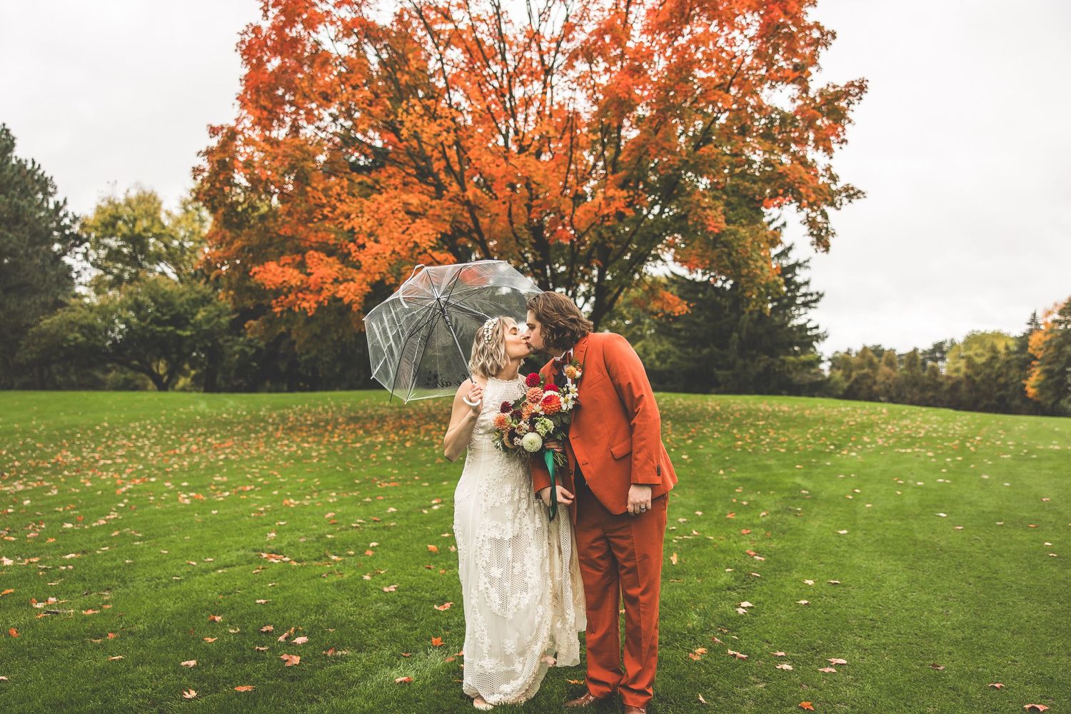 Wedding portrait beneath a dramatic orange maple tree in fall.