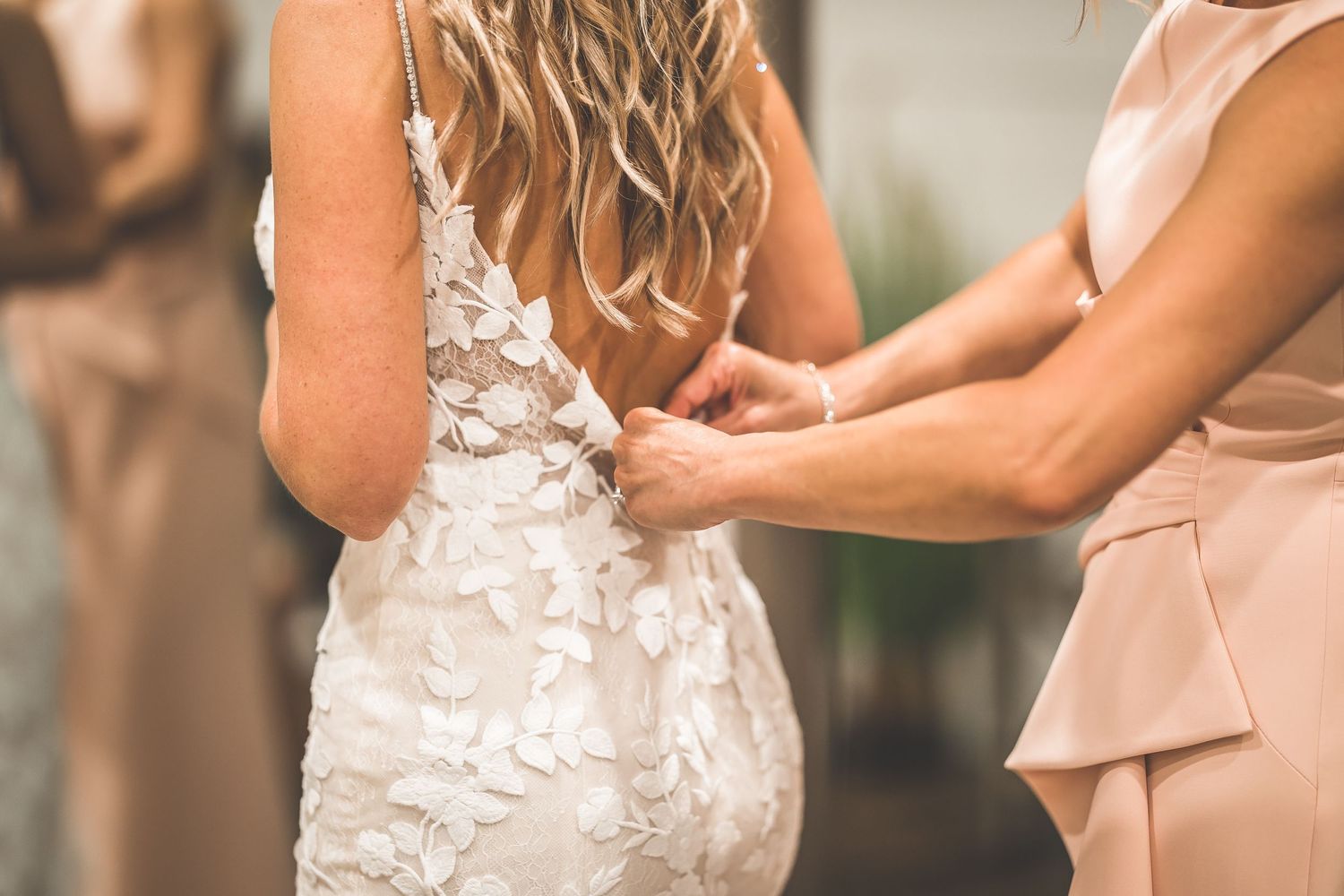 Close-up of intricate lace details on back of wedding dress being fastened.