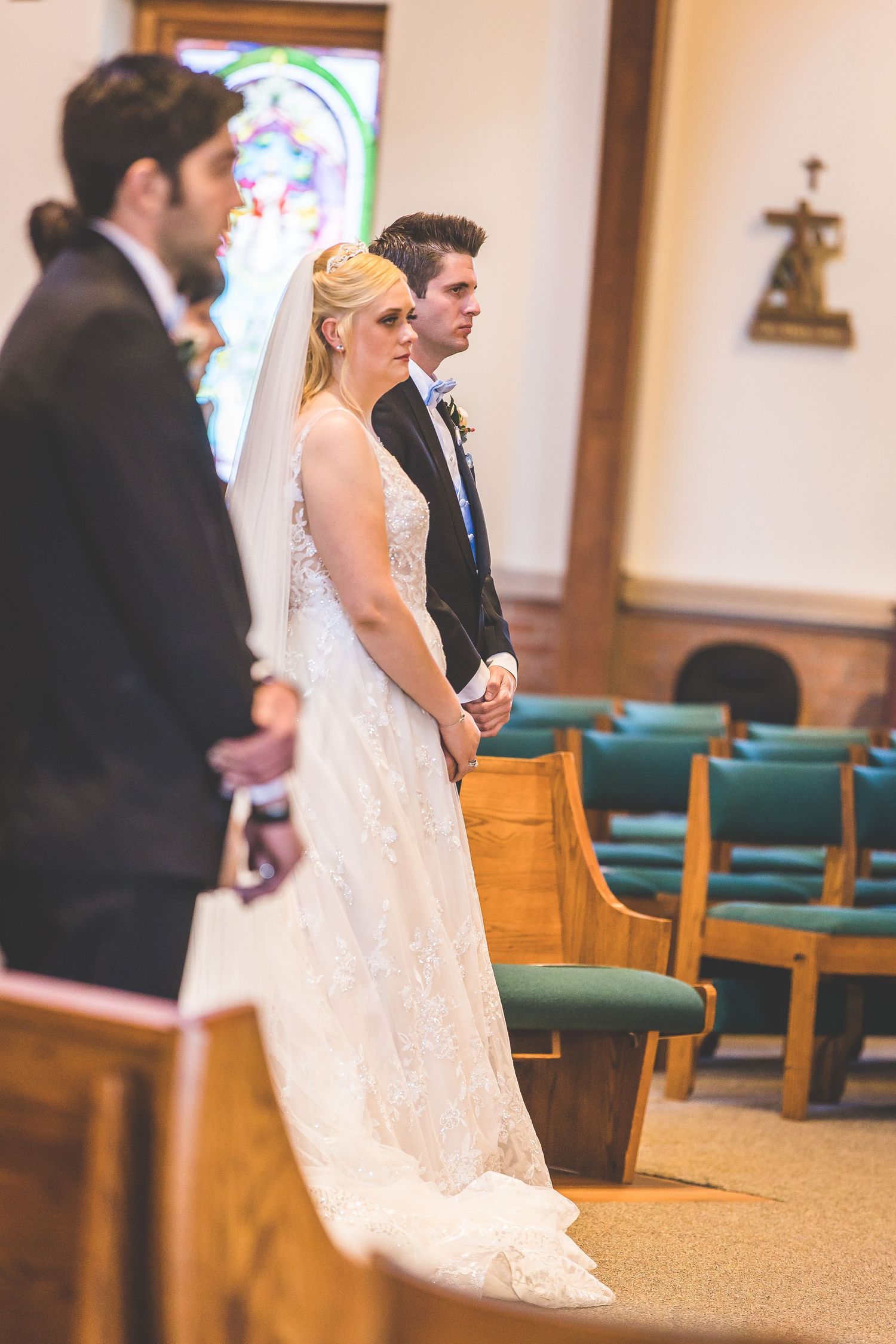 Wedding ceremony in progress showing white lace dress and church interior.