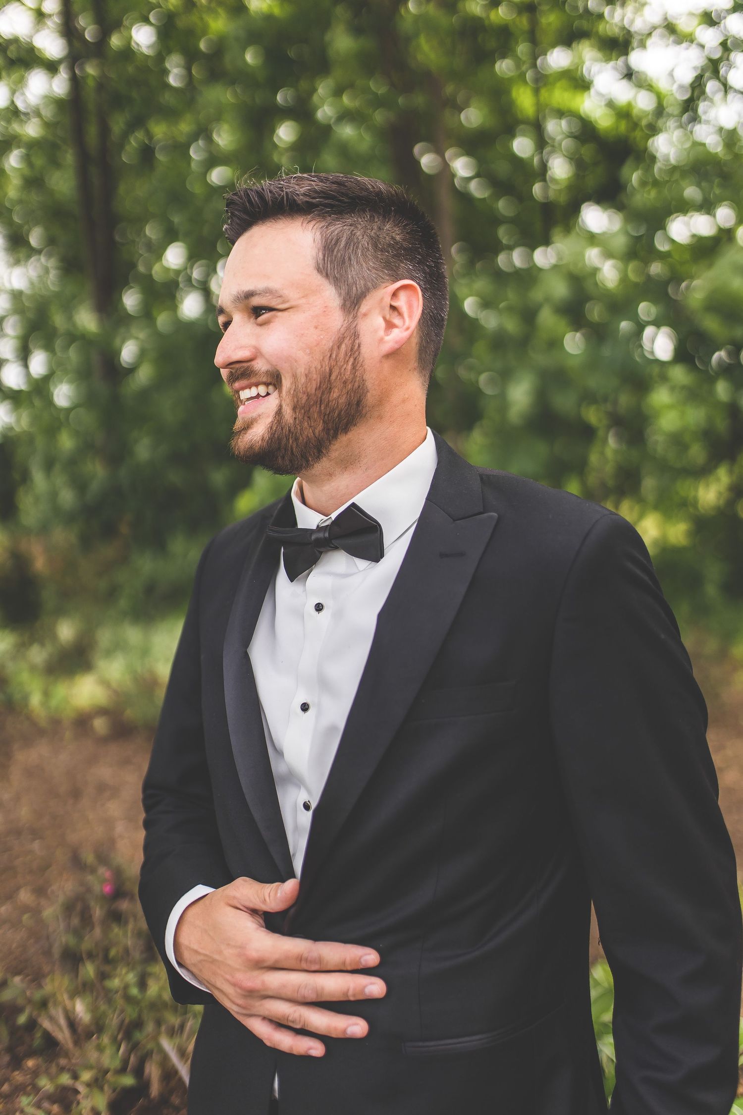 Candid moments of groomsmen laughing in classic black tuxedos.
