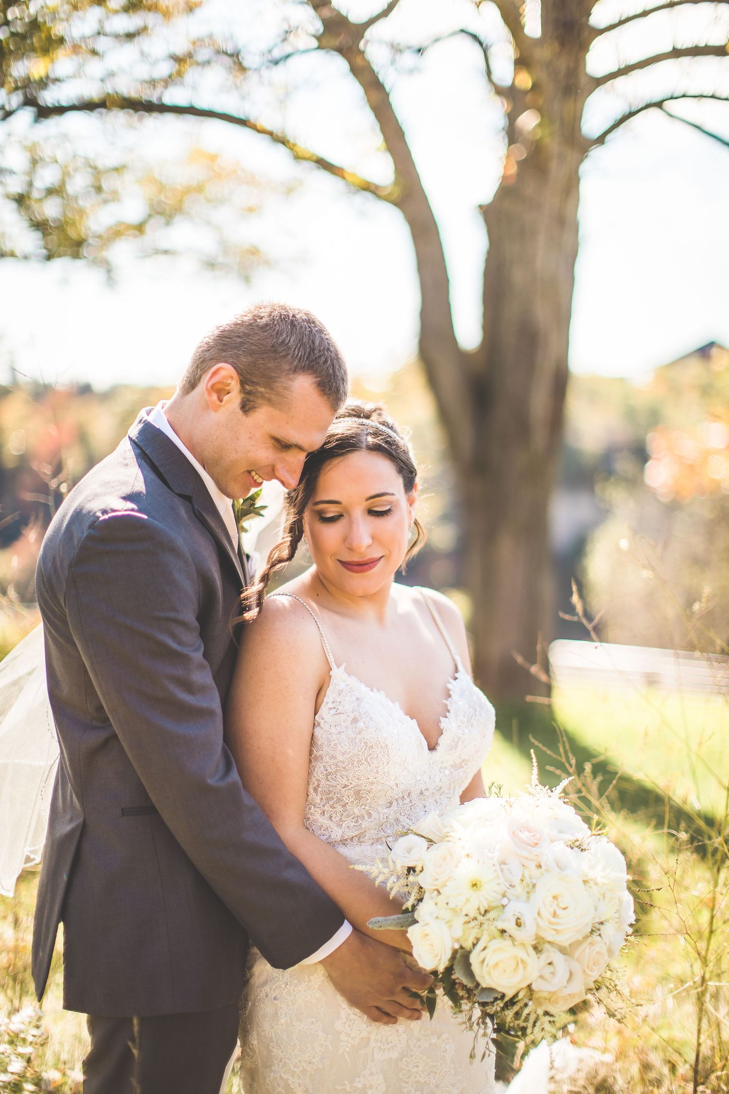 A romantic outdoor wedding portrait featuring a beautiful bouquet of white roses in an autumn setting.