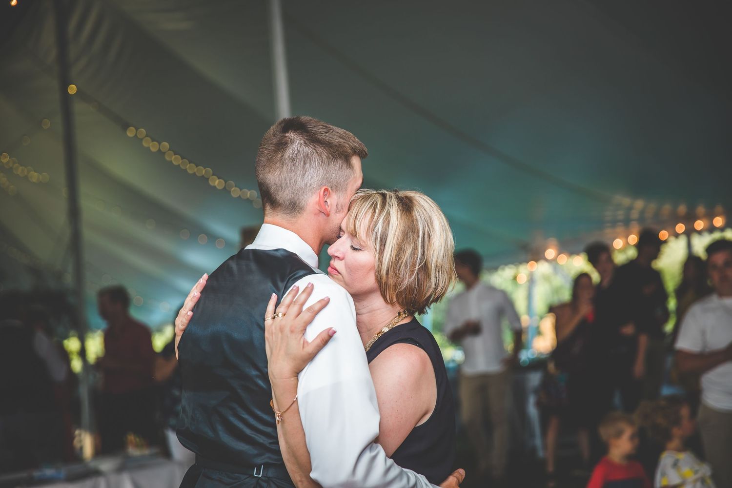 Wedding reception dance floor filled with guests celebrating under string lights.