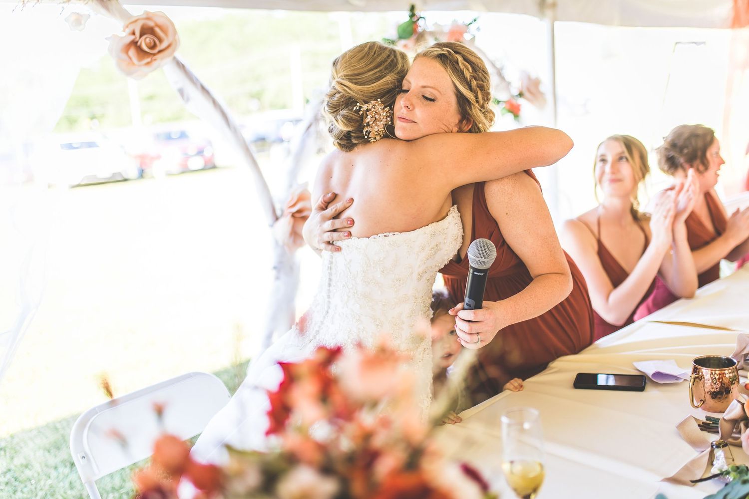 Wedding guests enjoying drinks and conversation at tables decorated with pink floral arrangements.