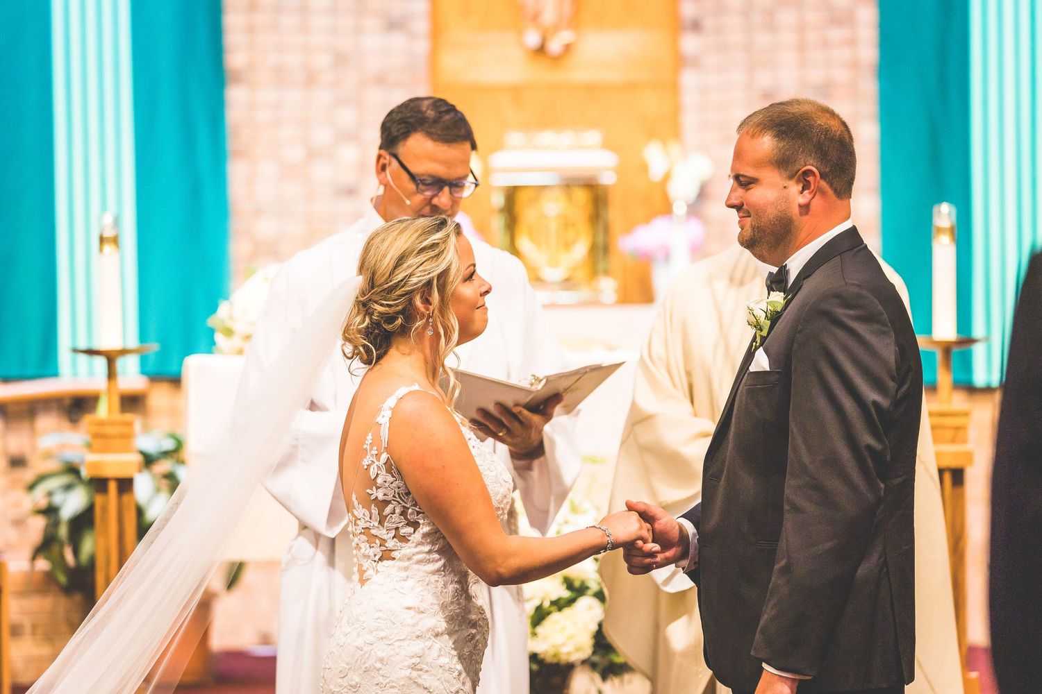 Wedding ceremony in progress with turquoise cross decorations against brick walls.
