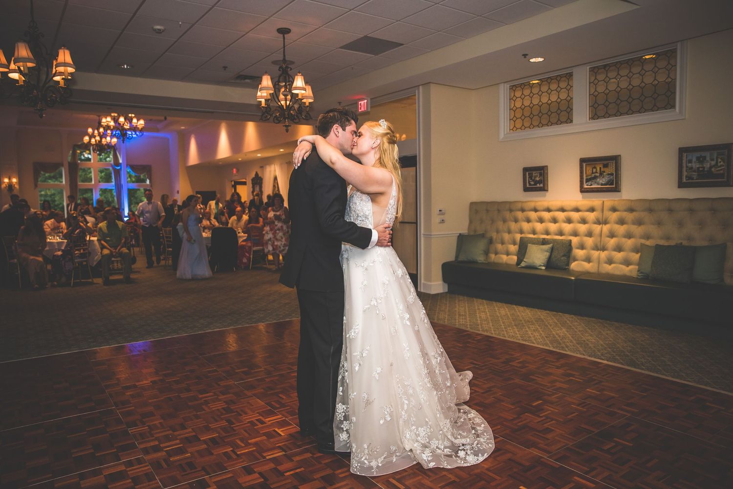 A wedding reception dance floor scene with elegant chandeliers and romantic lighting.