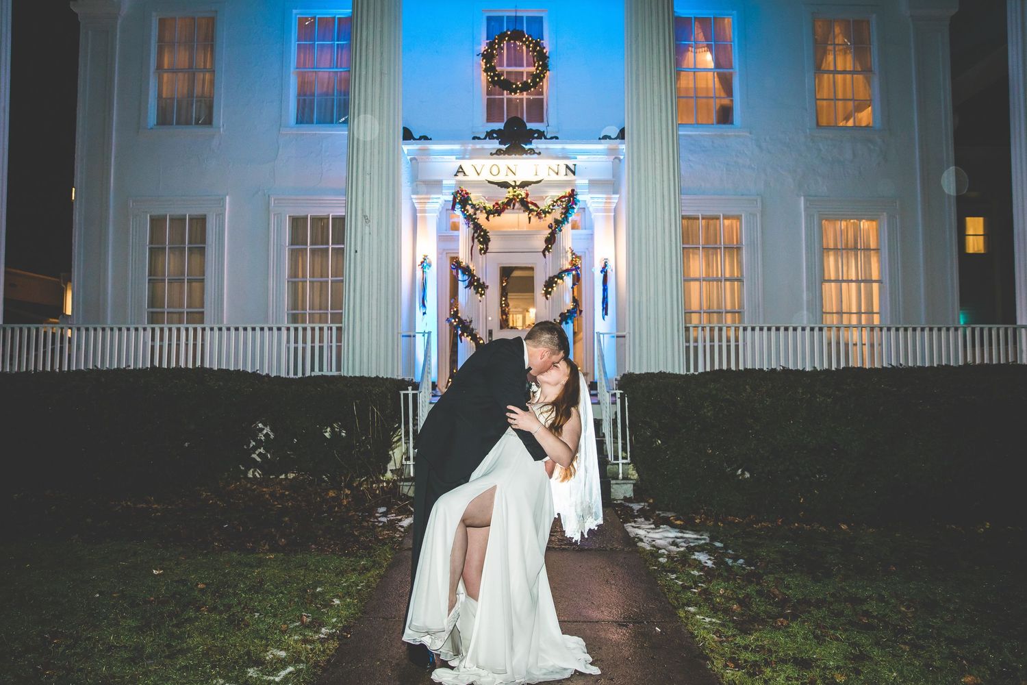 Exterior nighttime view of a grand white columned building illuminated in blue light.