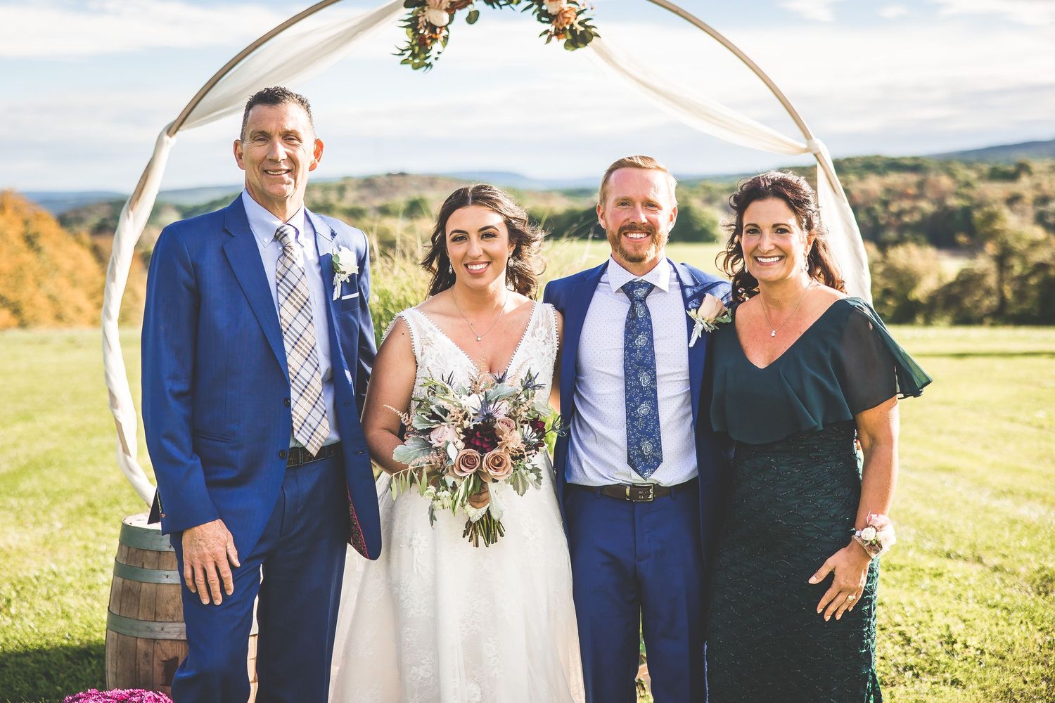 Wedding party members in navy and burgundy attire gather for formal portraits outdoors.