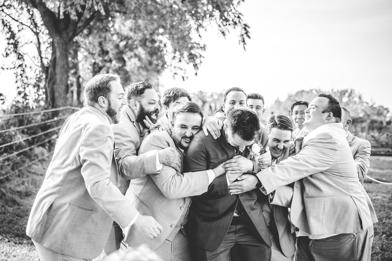 Black and white photo of groomsmen celebrating and toasting outdoors.