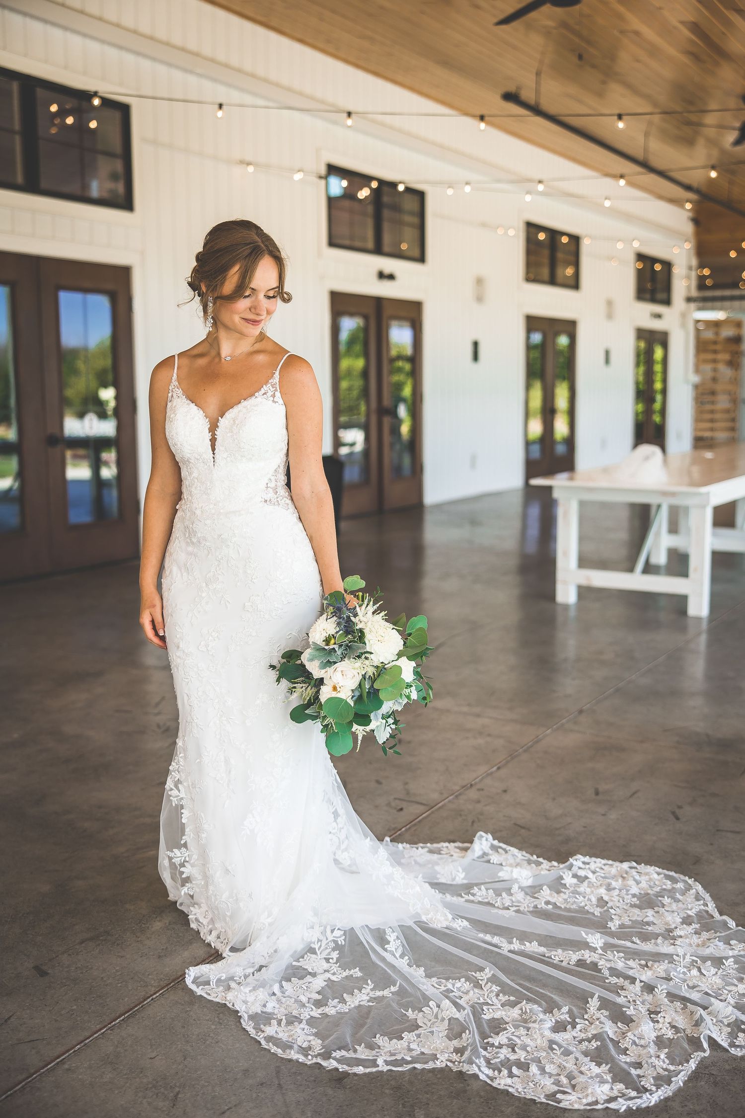 Elegant lace wedding dress with flowing train displayed in rustic indoor venue.