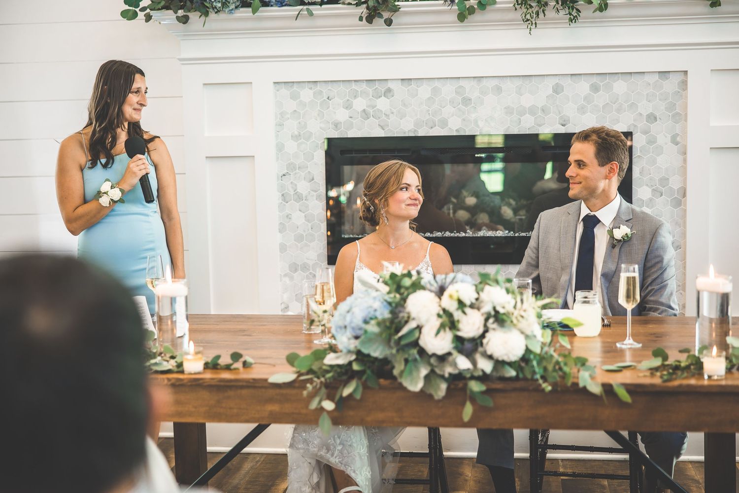 Wedding reception table adorned with white floral centerpieces and eucalyptus garland.