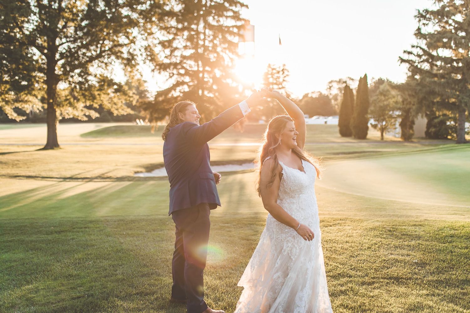 Couple dancing together on a golf course during golden hour.