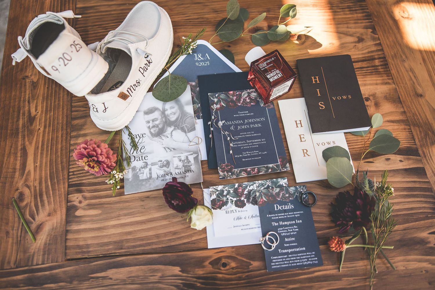 Wedding invitations and decorative elements arranged on rustic wooden table surface.