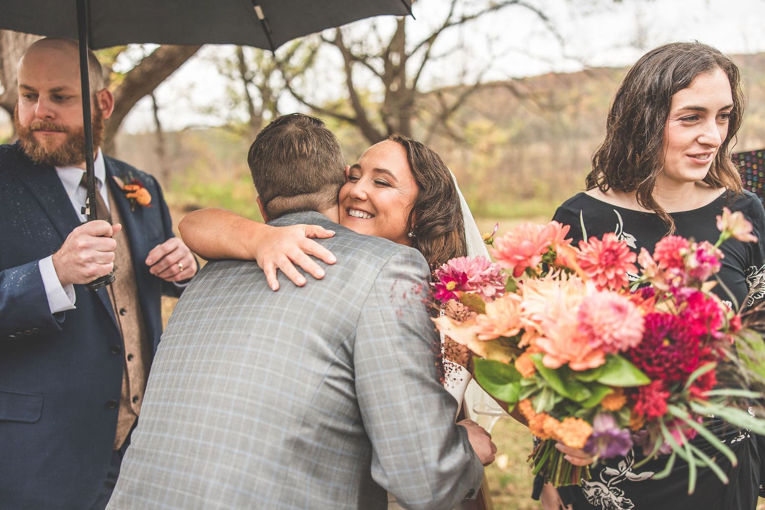 Wedding couple shares intimate moment during outdoor fall celebration with bright floral bouquet.