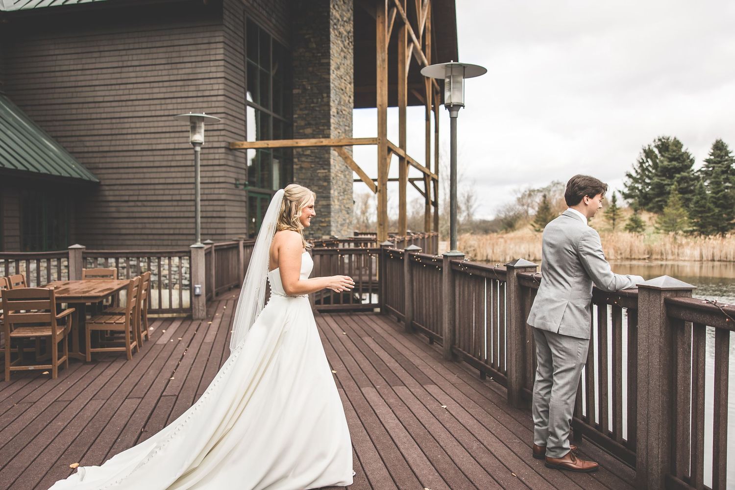 First look wedding moment captured on a rustic wooden deck with lake views.