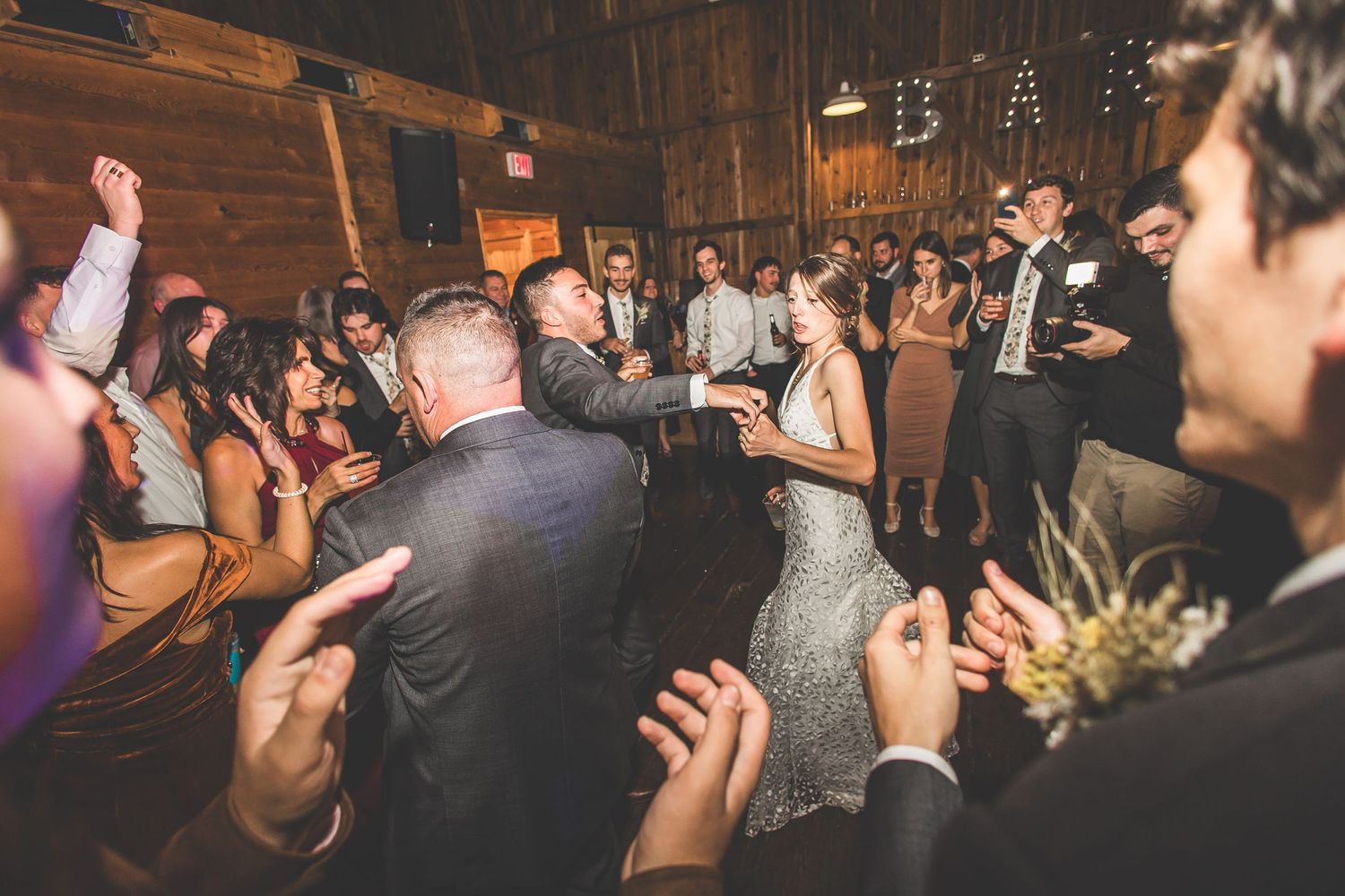 Guests enjoying a lively celebration on the dance floor of a rustic wooden barn venue.