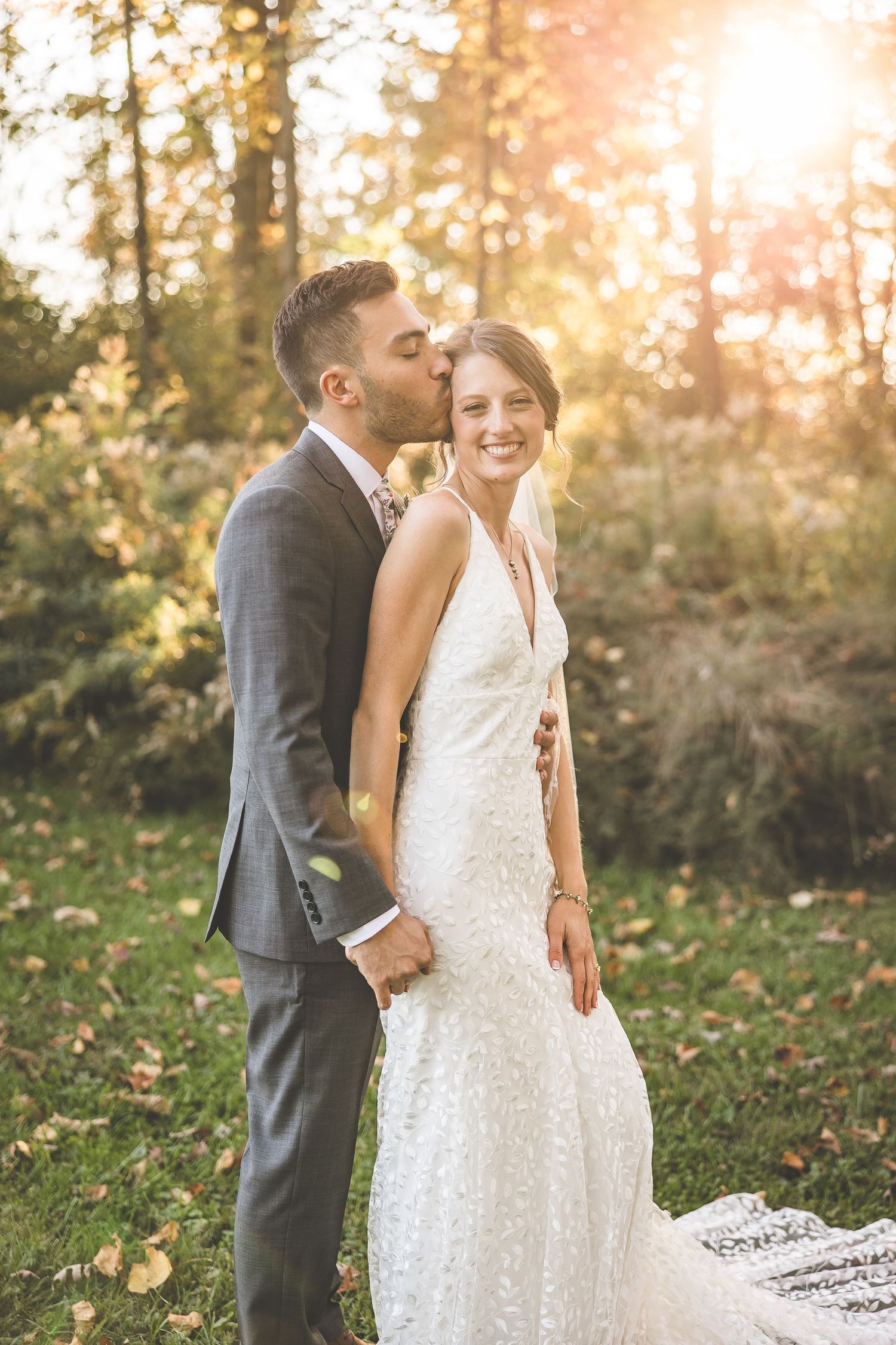Joyful wedding couple shares tender moment in autumn forest setting.