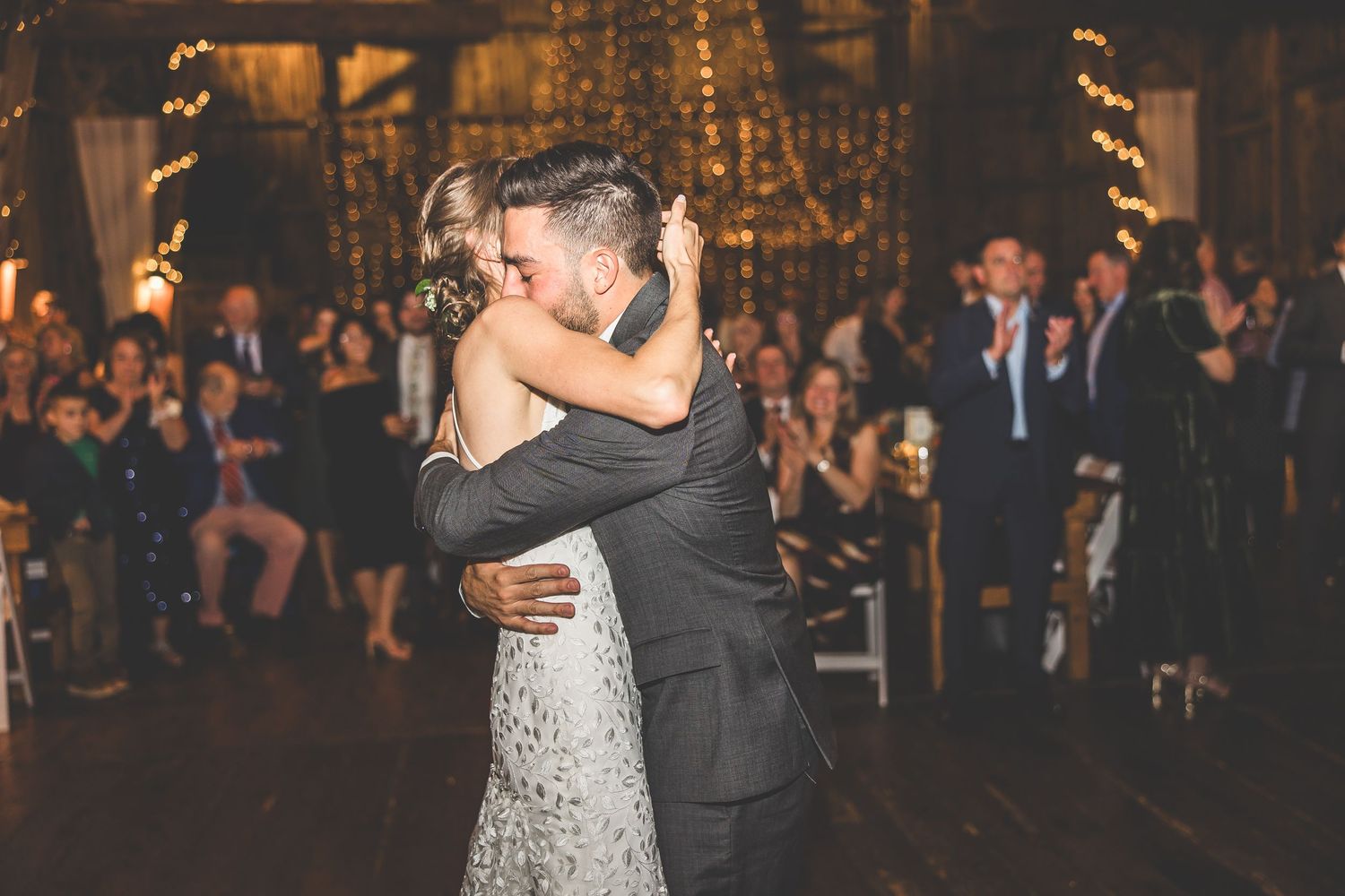 Couple sharing their first dance at a dimly lit wedding reception with twinkle lights.