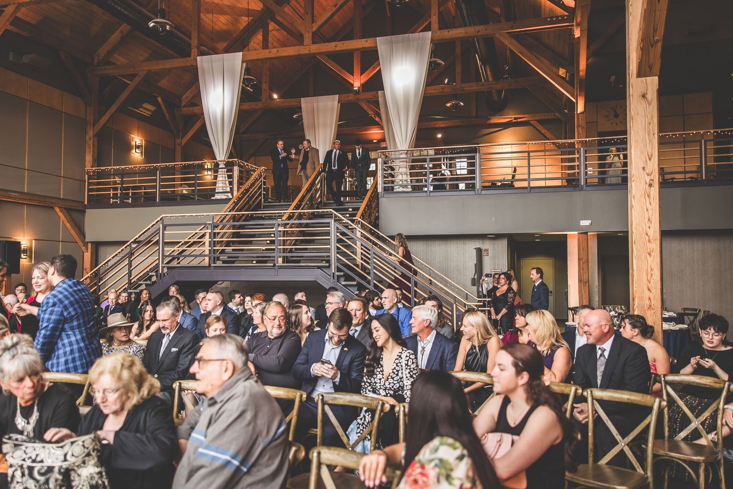 Wedding ceremony venue filled with guests seated in rustic industrial space.