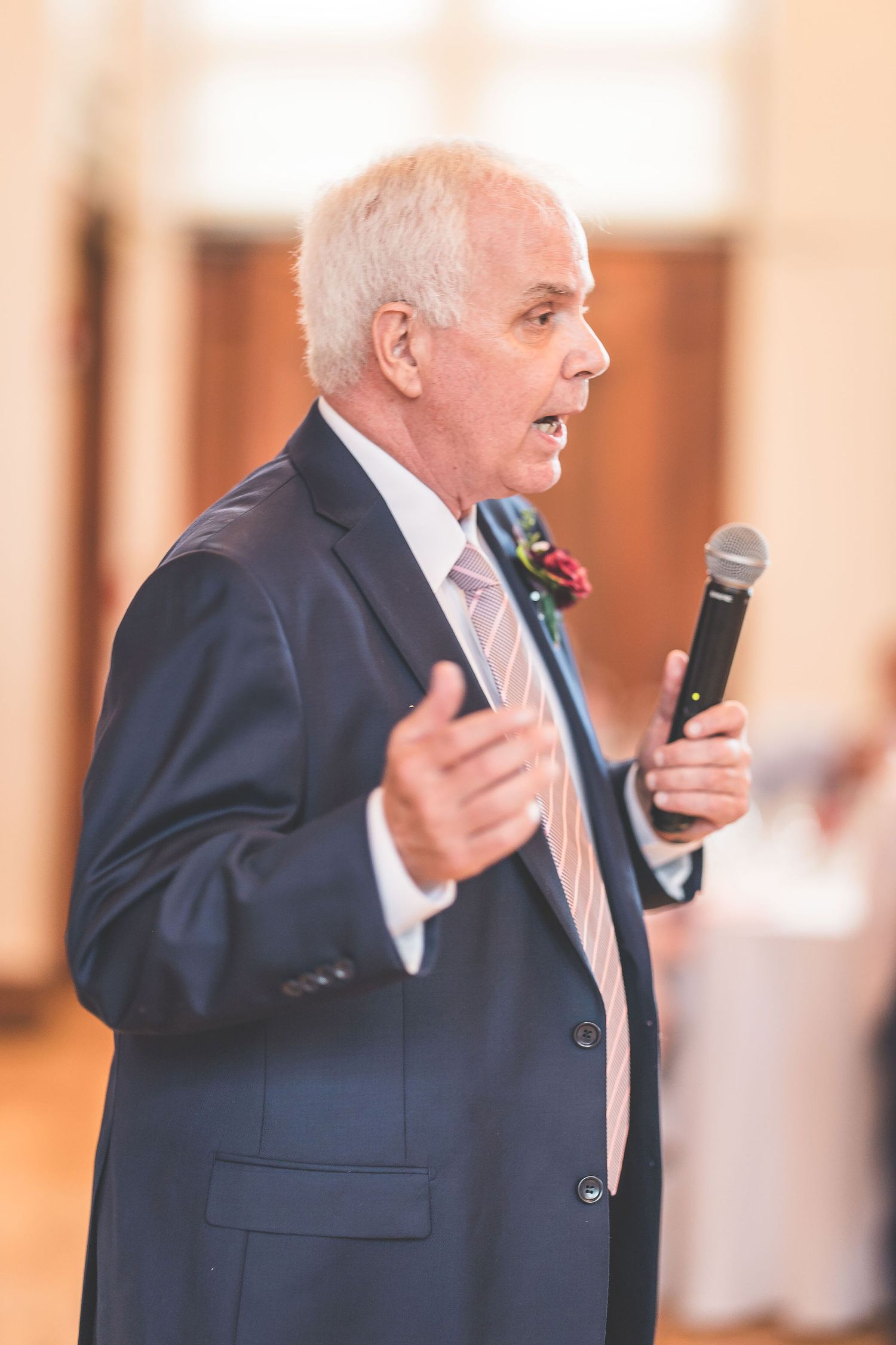 Speaker in navy suit gives emotional speech during formal event.