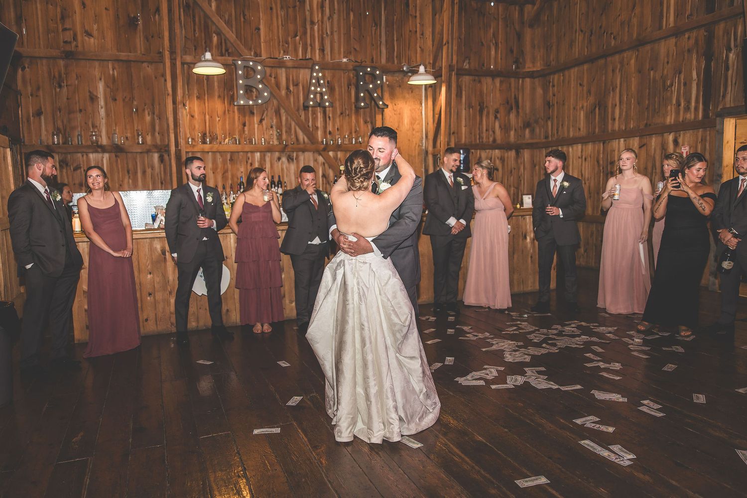 Wedding celebration in a rustic barn venue with string lights and wooden beam architecture.