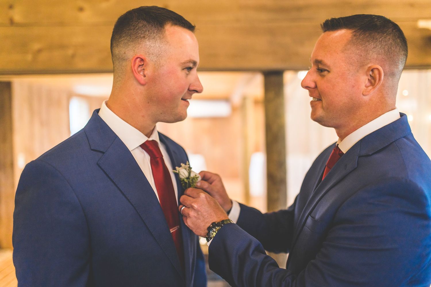 Wedding party members in navy suits and red ties sharing candid moments.