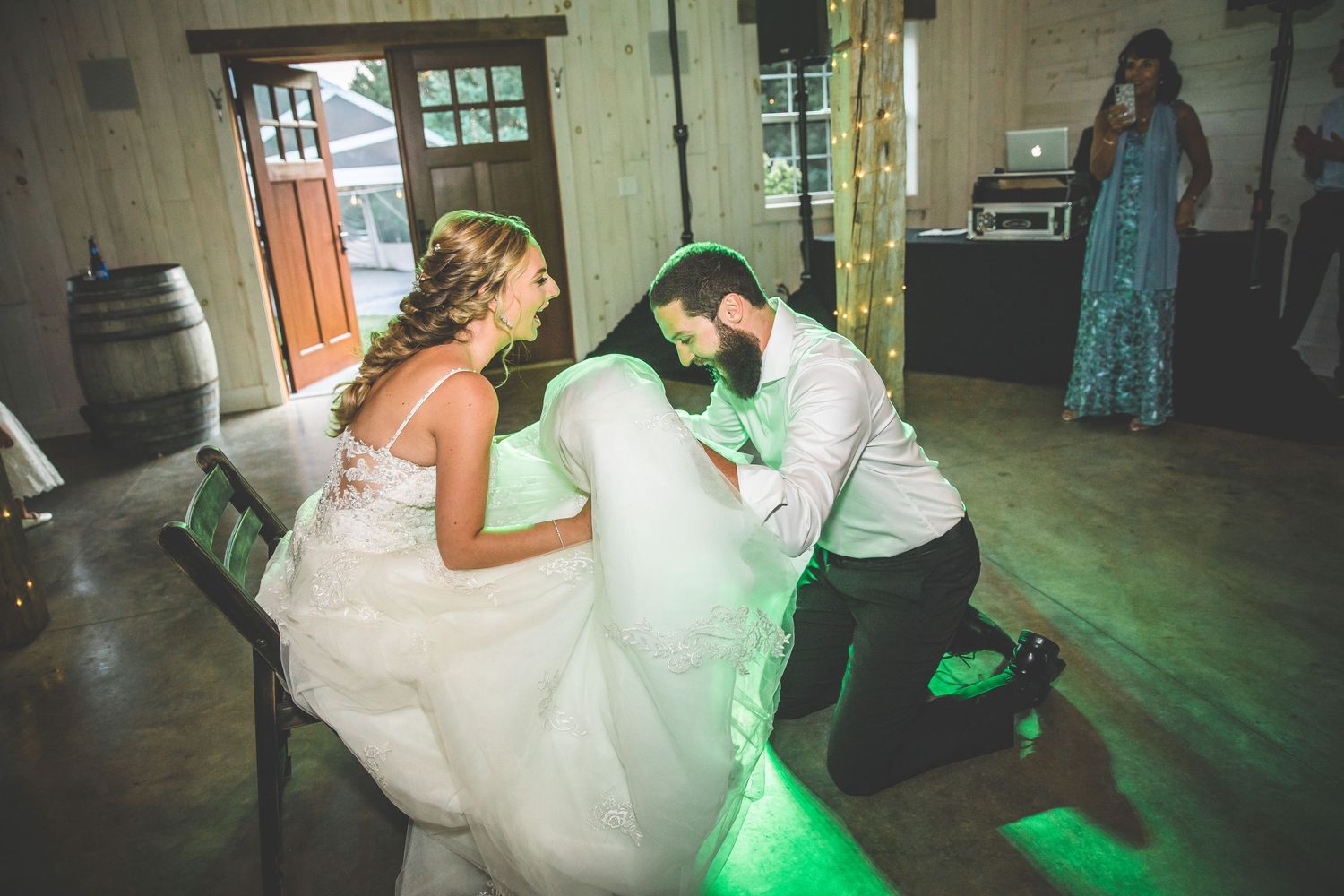 Wedding reception dance party with colorful lighting in a rustic barn setting.