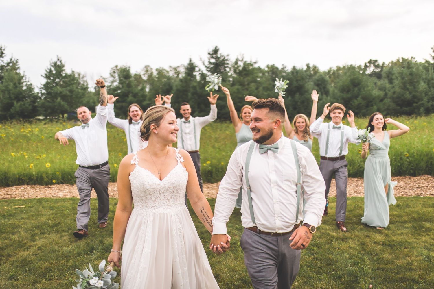 Wedding party members jumping and celebrating together in an outdoor setting.