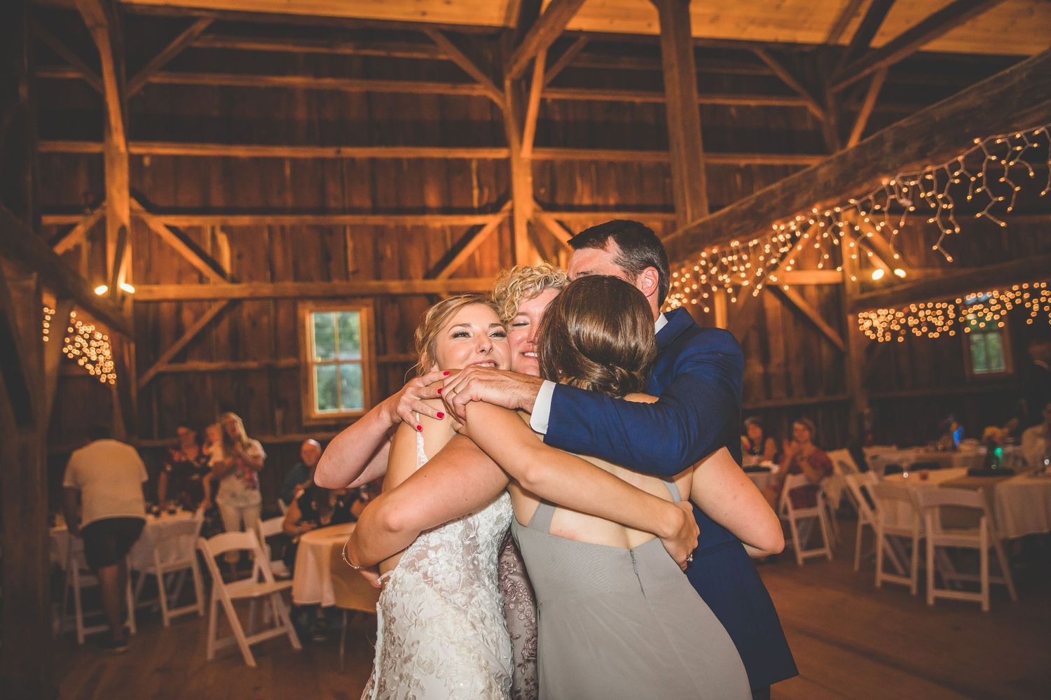 Wedding reception dance floor in rustic barn venue decorated with warm string lights creating romantic ambiance.