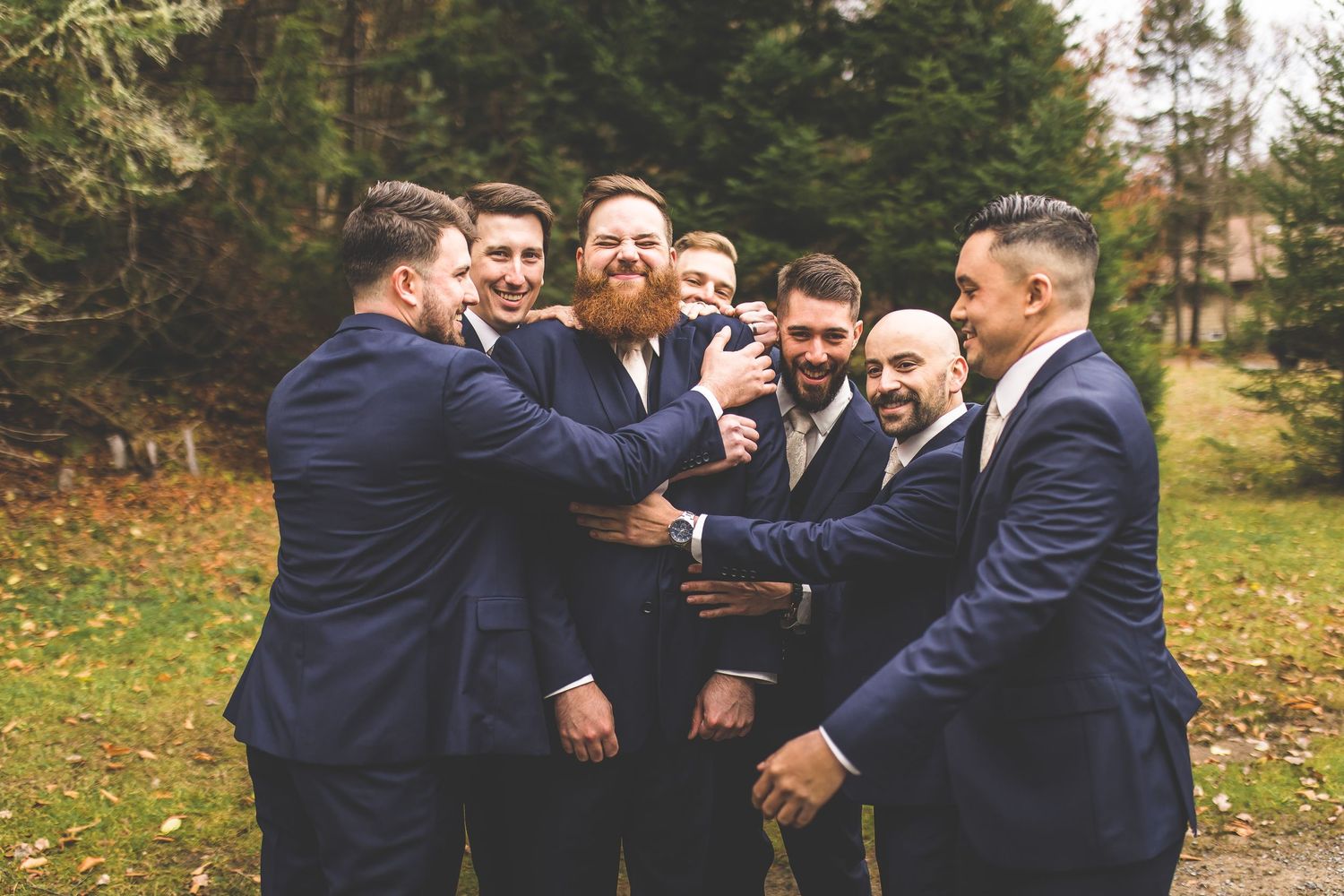 A group in navy suits share a celebratory toast outdoors during autumn.