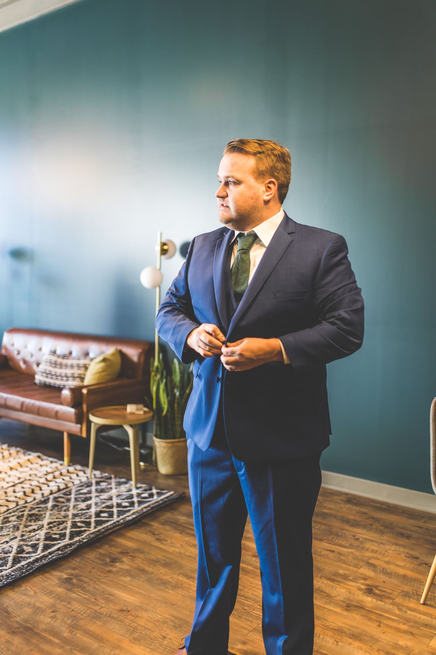 Person adjusting bright blue tie while getting dressed in formal attire.