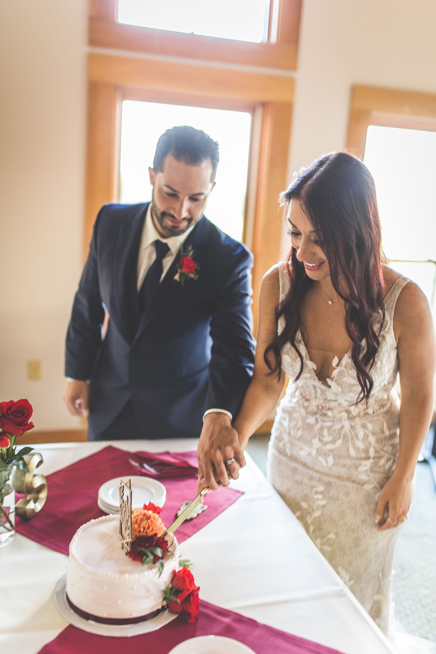 Newlywed couple sharing their first bite of wedding cake together at an indoor reception venue.