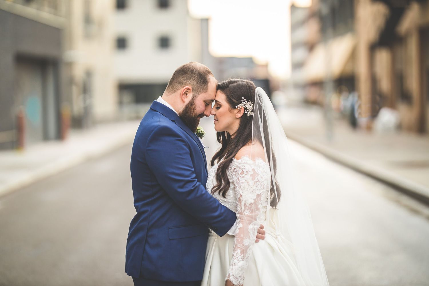 Romantic wedding portraits captured on quiet urban street with industrial backdrop.