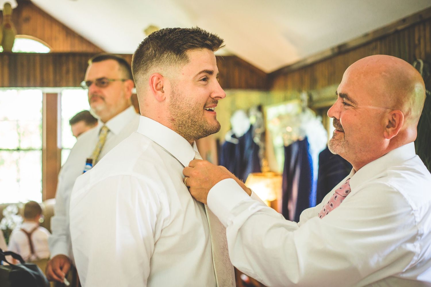 Helping adjust the groom's tie during wedding day preparations.
