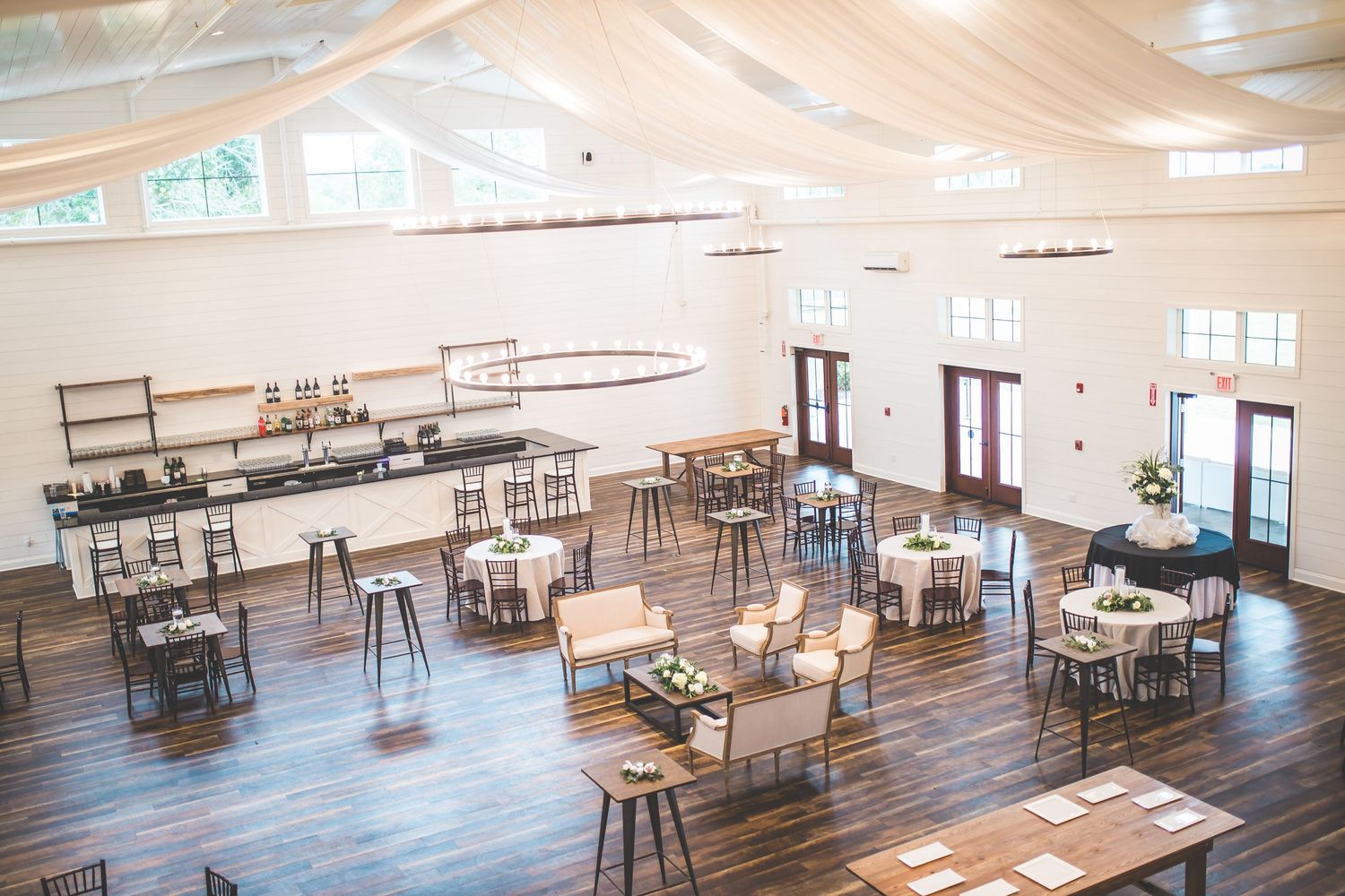Modern rustic reception venue interior with wooden floors and natural lighting.