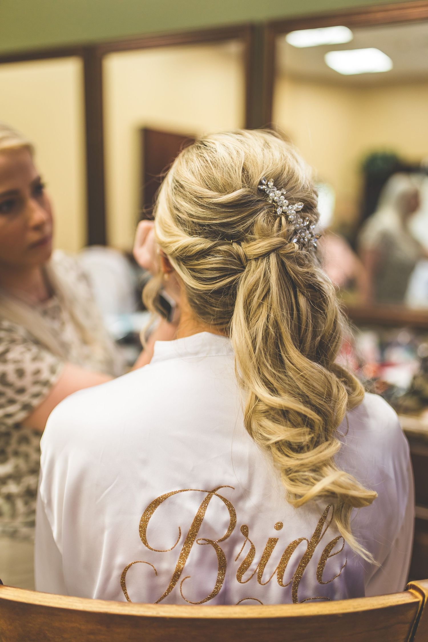 Bridesmaids wearing white robes with gold lettering during wedding preparations.